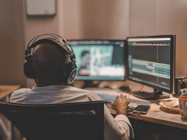 Back view of a man with headphones working on video editing in Lahore office. YouTube channel quote template: scope and fields