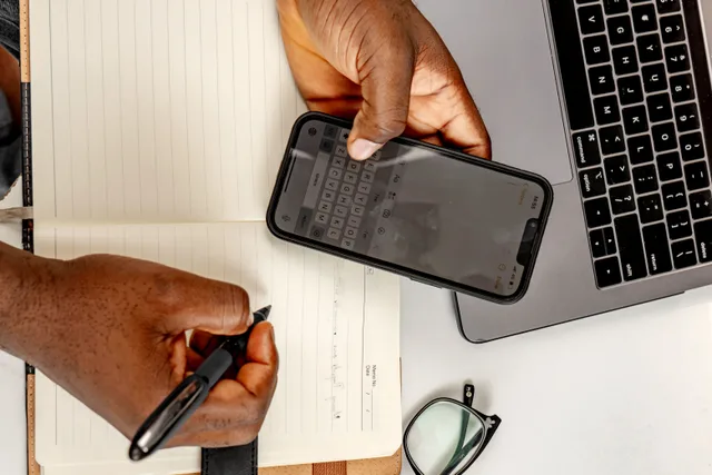 Business person multitasking with a smartphone and notebook at their desk. Which clauses in a YouTube channel sponsor contract actually matter?