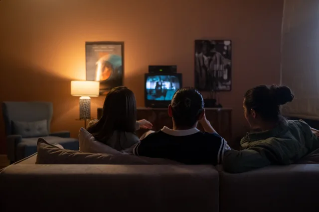 Three people enjoying a relaxed movie night at home, sitting on a couch in a cozy living room. 3 things to understand about Youtube channel trends
