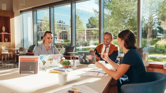 Three colleagues brainstorming with laptops in a well-lit office. Why CPMs differ across California, Texas and the Midwest for US YouTube channels