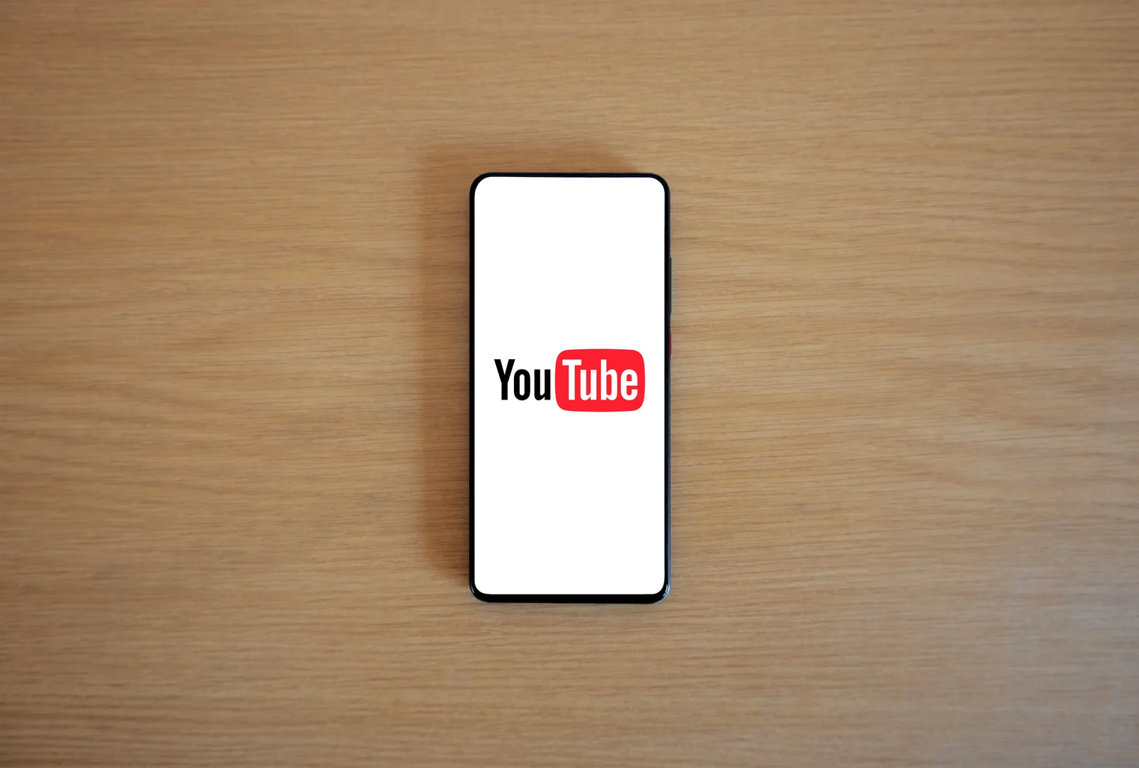 Top view of smartphone displaying YouTube logo on a wooden surface, showcasing modern technology. YouTube RPM by US State: Compare Ad Rates Across 50 States