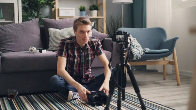 Young man sitting on the floor filming a vlog in a cozy living room with camera and tripod. YouTube Sponsorship Disclosure Rules Canada: Ad Standards vs CRTC